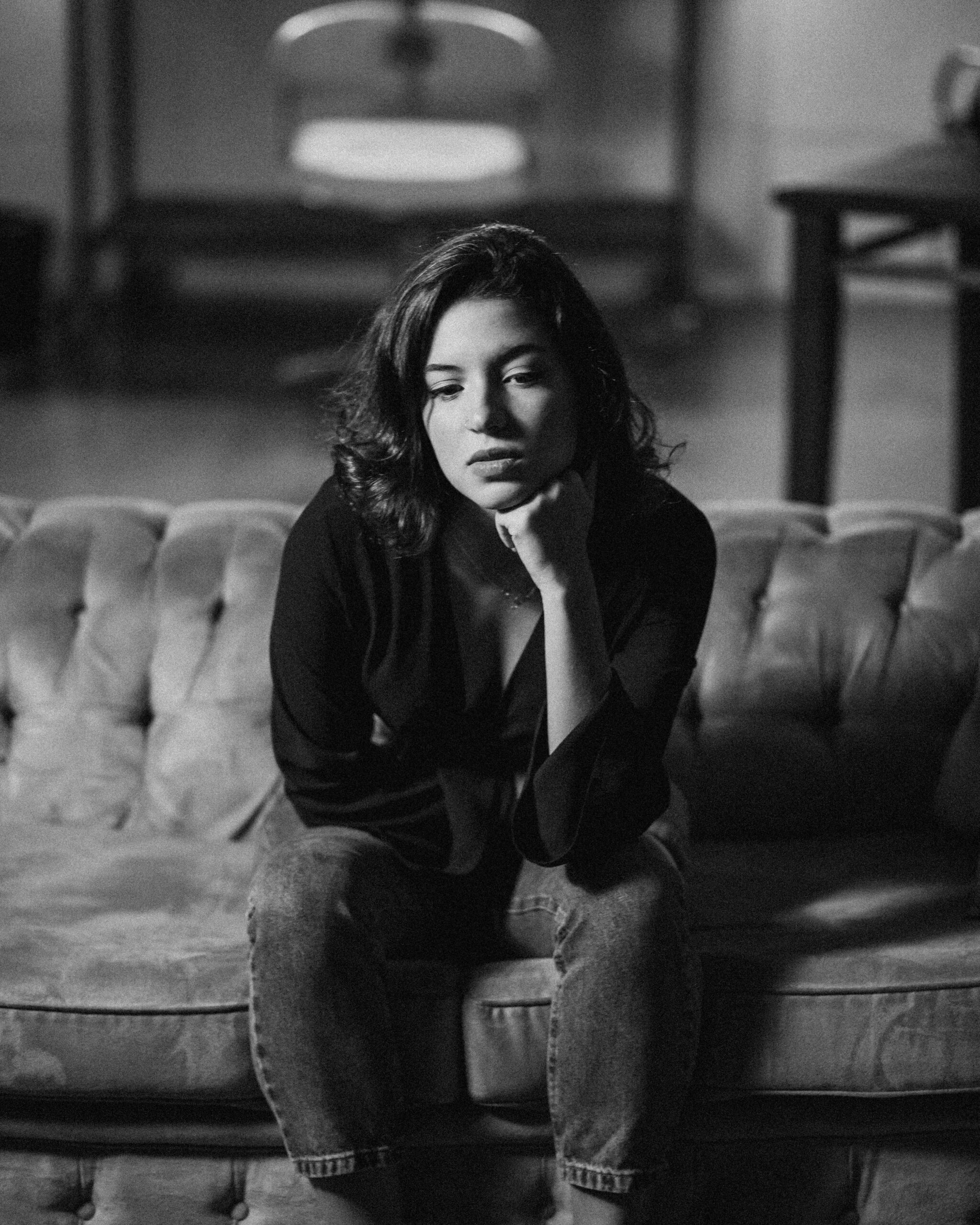 Monochrome portrait of a woman sitting on a sofa, deep in thought.