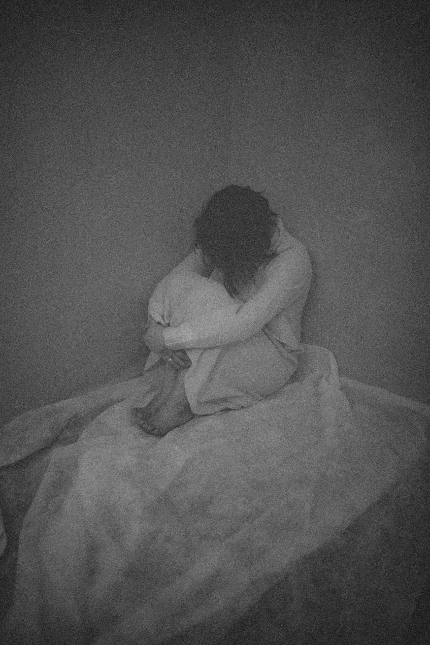 A black and white image capturing a woman sitting alone, conveying deep emotions.