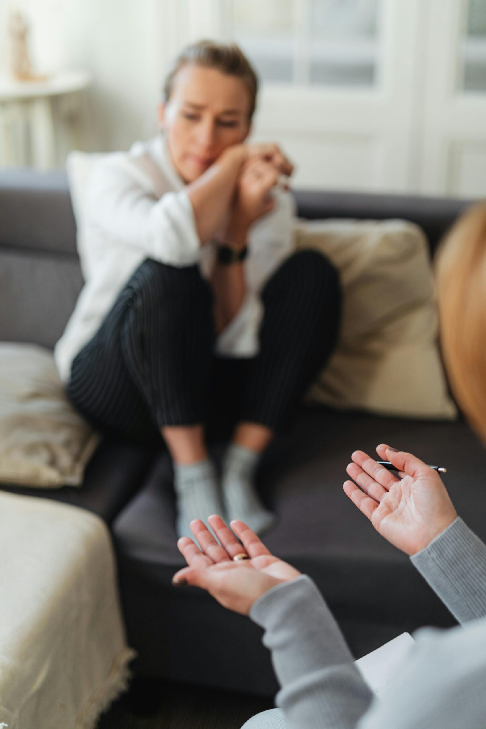 A woman in distress during a therapy session, showing emotional support and communication.