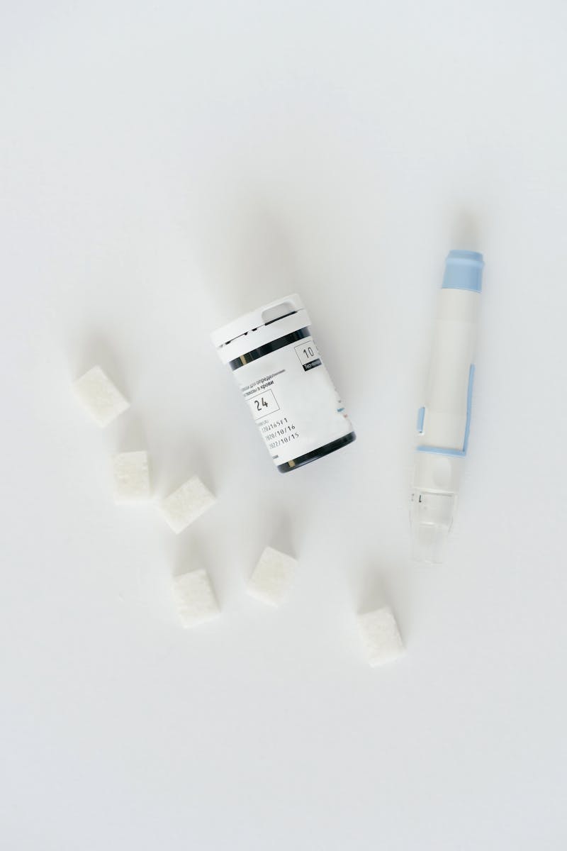 A still life image of diabetes testing supplies alongside sugar cubes, symbolizing sugar control.